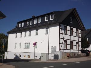 a white and black building with a black roof at Deutsches Haus in Willingen