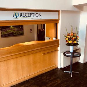 a reception desk with a vase of flowers on it at Stoneleigh Park Lodge in Leamington Spa