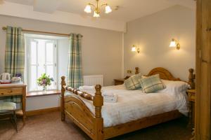 a bedroom with a bed and a desk and a window at The Marton Arms in Ingleton