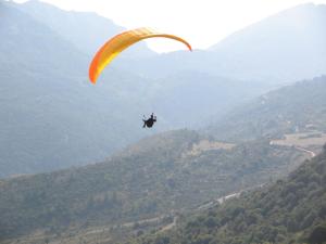 a person riding a parachute in a valley at Maison de la Fontaine in Embres-et-Castelmaure