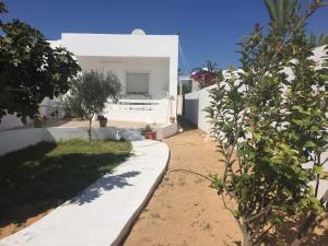 ein weißes Haus mit einem Garten mit Bäumen davor in der Unterkunft Maison Dhiefa in Midoun