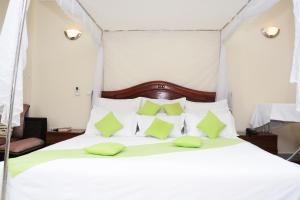 a bedroom with a white bed with green pillows at Five to Five Hotel in Kigali