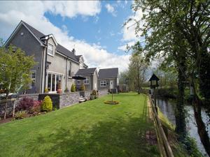 a house with a grass yard next to a river at Crowfield Country House in Aghadowey
