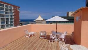 balcón con mesa, sillas y sombrilla en Grande 4Q com 2Suites e Terraço na Barra perto praias, en Salvador