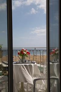 een tafel met witte stoelen en bloemen op een balkon bij Hotel Ancora in Rimini