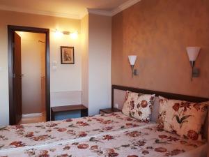 um quarto com uma cama com colcha floral em Family Hotel Radiana em Sozopol