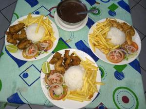 tres platos de comida con arroz y papas fritas en una mesa en Pousada Tony Montana en Praia de Araçatiba