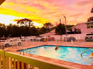 una persona en una piscina con la puesta de sol en el fondo en Sky Suites, en Tybee Island