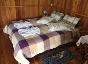 um quarto com uma cama com um cobertor e almofadas em Pousada Sabor da Roça em Urubici