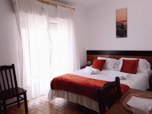 a bedroom with a bed with white and red pillows at Casa Dorita in Odeceixe