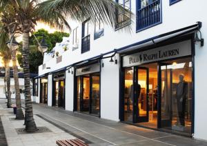 a row of store fronts on a street with a palm tree at Casa Zen in Puerto Calero