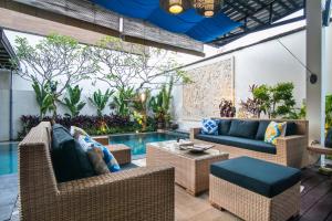 a patio with wicker furniture and a swimming pool at Sunset Paradise Jimbaran 3003 in Jimbaran