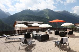 eine Gruppe von Stühlen und Sonnenschirmen auf einer Terrasse mit Bergen in der Unterkunft Schorta's Alvetern in Ardez