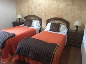 two beds in a hotel room with orange sheets at La Casa Verde in Las Casas