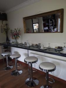 una barra con tres taburetes y un espejo en GoldenDawn Guest House, en Citywest