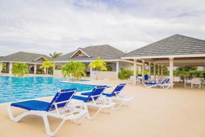a group of blue and white chairs next to a swimming pool at Coolshade Villa Mahoe II Ocho Rios in Ocho Rios