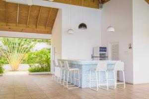 a kitchen with a blue counter and white stools at Coolshade Villa Mahoe II Ocho Rios in Ocho Rios