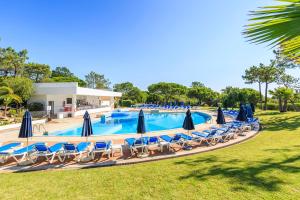 a large swimming pool with chairs and umbrellas at Victory Village 2A in Quinta do Lago
