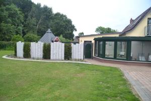 una casa con una valla blanca y un patio en Radlerwohnung bei Familie Saupe en Schaprode