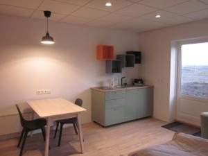 a room with a table and a kitchen with a window at Apartment Brekka í Lóni in Stafafell