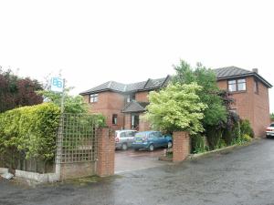 a house with cars parked in a parking lot at Herdshill Guest House in Wishaw