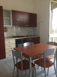 a kitchen with a wooden dining table and chairs at Case Vacanze Panarea by CivicoVentiquattro in Cava dʼAliga