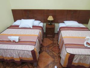um quarto de hotel com duas camas e um candeeiro em Alojamiento El Cardenal em Iquitos