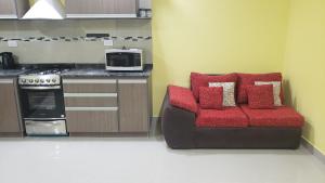 a kitchen with a couch with red cushions and a microwave at Complejo EL ANGEL in Río Colorado