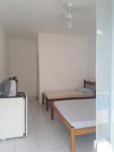 a room with two beds and a table in it at Suite Recanto Cheiro Verde in Caraguatatuba