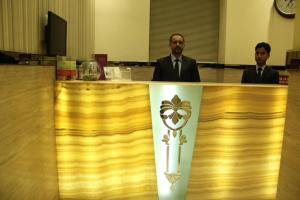 two men in suits are standing behind a counter at Hotel Ripon Palace in Mumbai