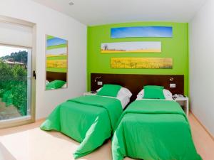 two beds in a room with green walls at Hotel La Sèquia Molinar in Campdevánol