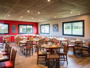 una sala da pranzo con tavoli, sedie e pareti rosse di ibis Avranches Mont St Michel a Saint-Quentin-sur-le-Homme