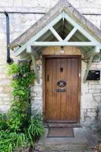 a wooden door on a stone house with awning at Half-pint Cottage in Stroud