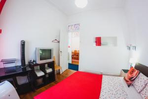 a living room with a red bed and a television at Farol de Vida in Coimbra