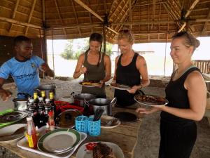 un grupo de personas preparando comida en una tienda en Kasenyi Lake Retreat & Campsite en Kasese