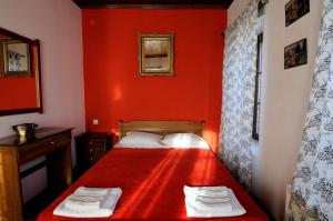 ein rotes Schlafzimmer mit einem Bett mit zwei Handtüchern darauf in der Unterkunft Philippos Hotel in Psarádes
