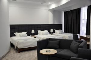 a hotel room with two beds and a couch at Parliament Palace Hotel in Khujand
