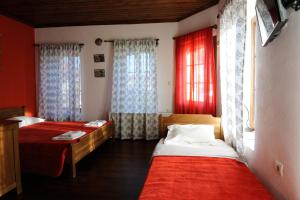 2 Betten in einem Zimmer mit roten Wänden und Fenstern in der Unterkunft Philippos Hotel in Psarádes