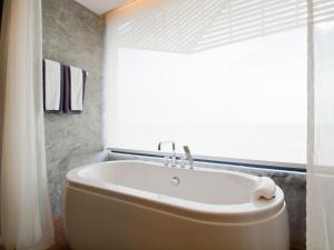 a white tub in a bathroom with a window at The Now Hotel - SHA Extra Plus in Jomtien Beach
