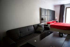 1 dormitorio con sofá negro y cama roja en Concept Suites, en Alicante