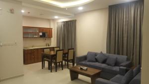 a living room with a couch and a table and a kitchen at Al Nakhla Aparthotel in Al Hofuf