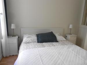 a white bed with a blue pillow on top of it at 8 Rue de la Petite Bilange " Maison du Centre" in Saumur +1 photo