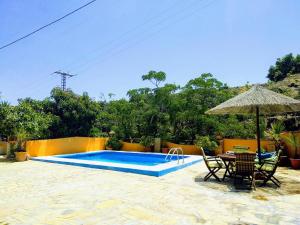 een zwembad met een tafel en stoelen en een parasol bij Finca El Valle in Nerja