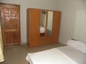 1 dormitorio con armario de madera y cama en Biso Inn, en Alimosho 14 fotos más