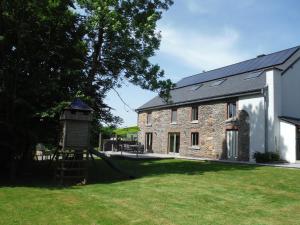 une maison en pierre avec une aire de jeux dans la cour dans l'établissement Gîte Au Coeur de Champlon, à Champlon