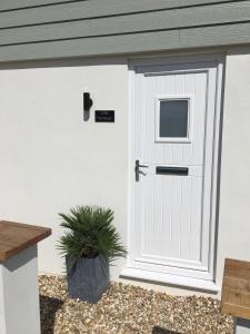 a white garage door with a window and a plant at Little Fernleigh in Perranporth