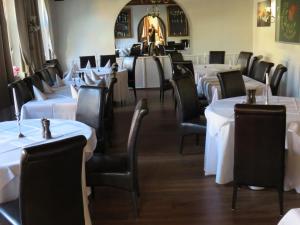 uma sala de jantar com mesas brancas e cadeiras pretas em Gasthof Einhaus em Borken