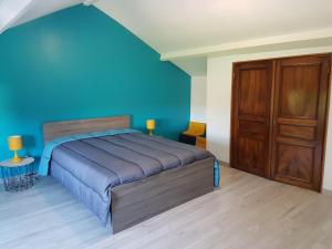 a blue bedroom with a bed and a wooden closet at La Cantraigne in Audembert