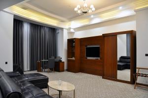 a living room with leather furniture and a flat screen tv at Parliament Palace Hotel in Khujand