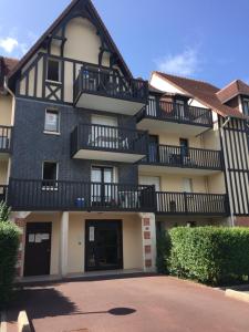 ein Gebäude mit Balkon auf der Seite in der Unterkunft T2 jardinet, accès direct plage in Cabourg